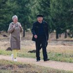 Happy senior couple strolling along a park path on a pleasant spring day.